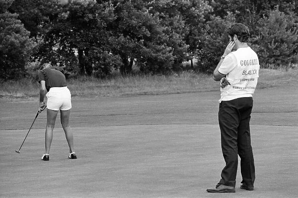 A man watches a woman playing golf during the Colgate European Women