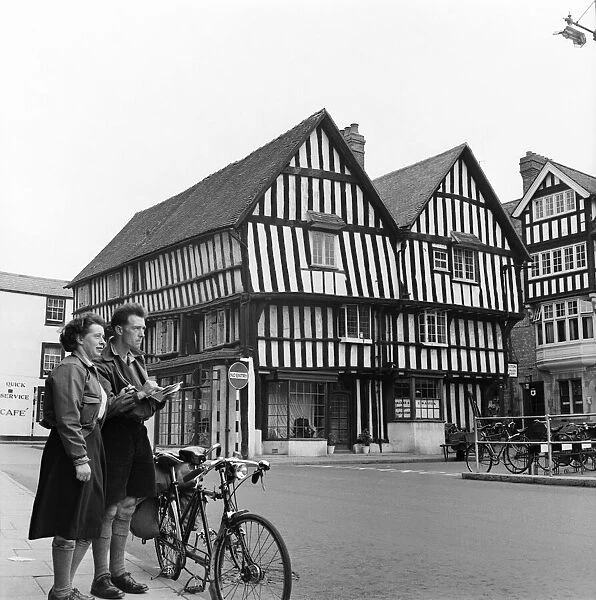 Man and woman sightseeing in an English town with Tudor style houses. October 1952 C5252