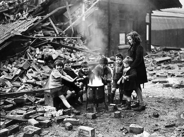 Manchester children warm themselves by the brasier following an air raid on the city