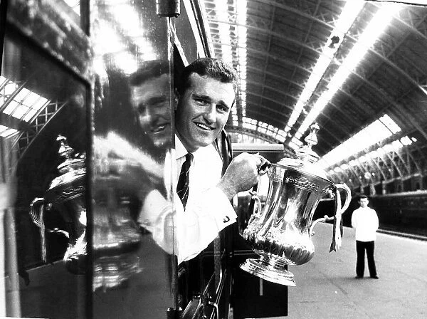 Manchester United captain Noel Cantwell leaning from the train with the FA cup trophy at