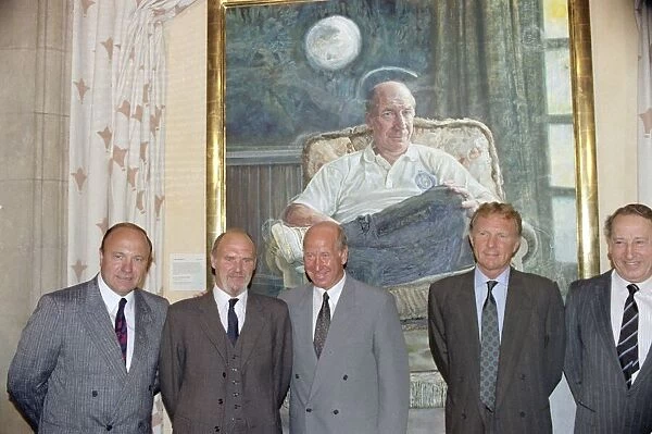 Manchester United director Bobby Charlton (centre) standing in front of a painting of him
