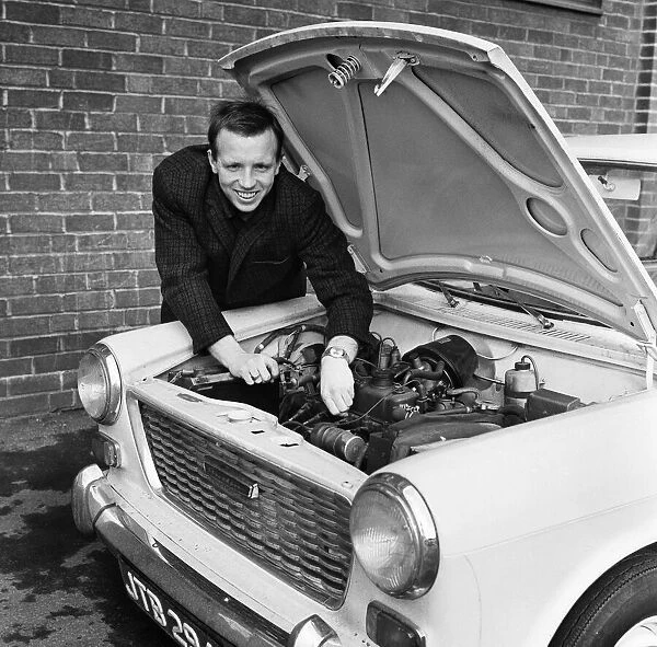 Manchester United and England footballer Nobby Stiles tends to his car engine at Old