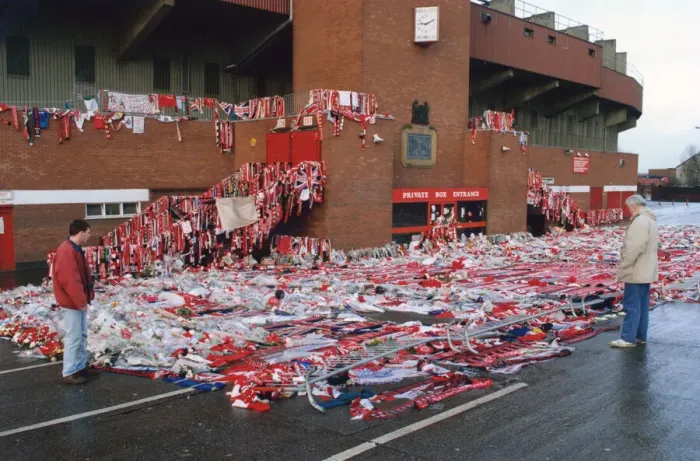 Framed Print : Manchester United fans bow their heads in respect as they observe collections of scarves Framed Print : Manchester United fans bow their heads in respect as they observe collections of scarves