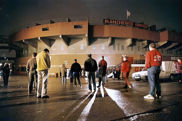 Manchester United fans bow their heads in respect during a slient vigil outside Old