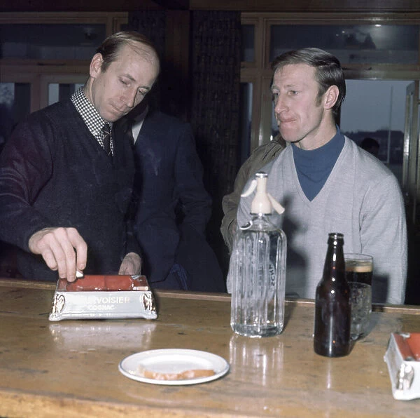 Manchester United footballer Bobby Charlton puts out a cigarette in the ash try as he