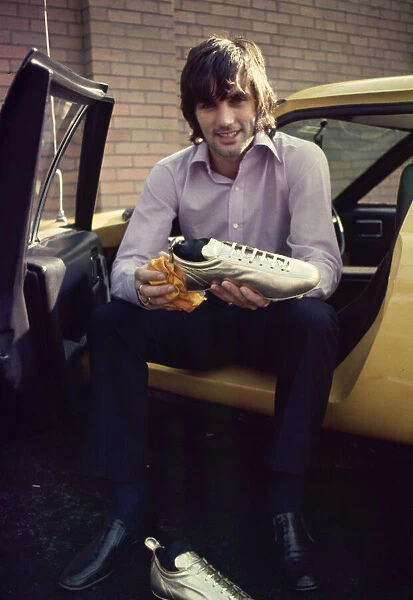 manchester United footballer George Best shows of his gold painted football boots which