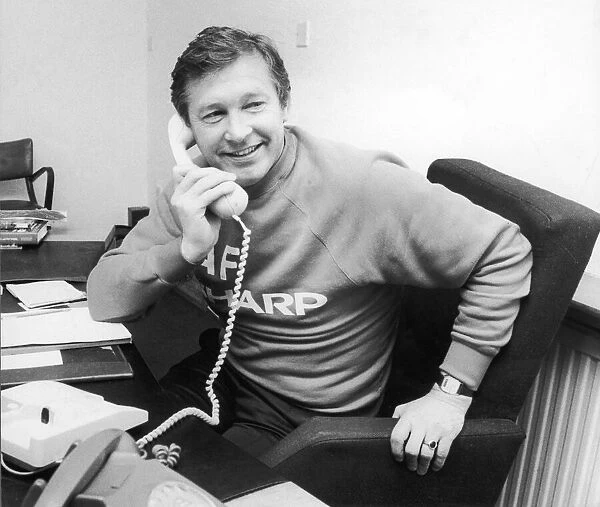 Manchester United manager Alex Ferguson speaking on the telephone in his office