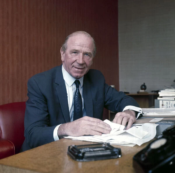 Manchester United manager Sir Matt Busby sitting at the desk in his office at Old