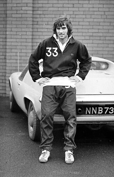 Manchester United star George Best poses next to his Lotus Europa car after a training