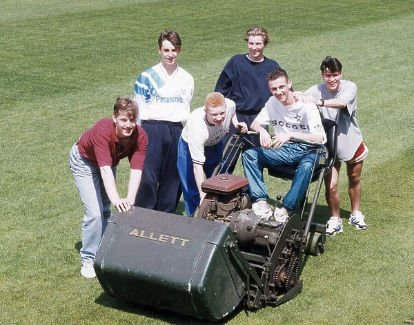 Manchester United youth team players surrounding a lawnmower on the pitch at The Cliff