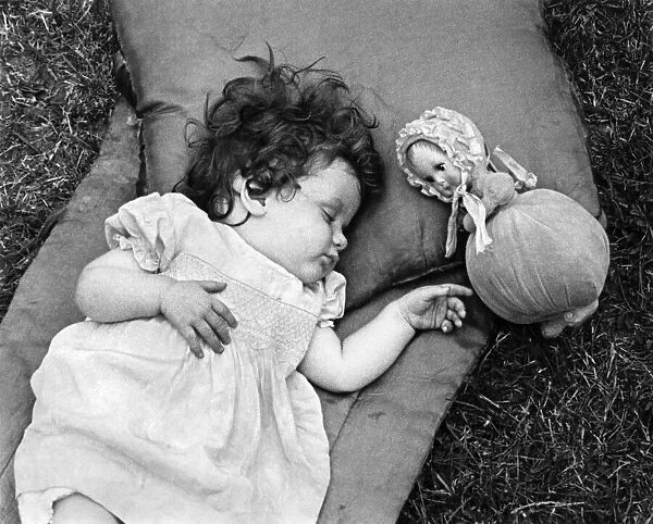 Margaret Anderson Johnson takes a nap next to her doll. 30th June 1941