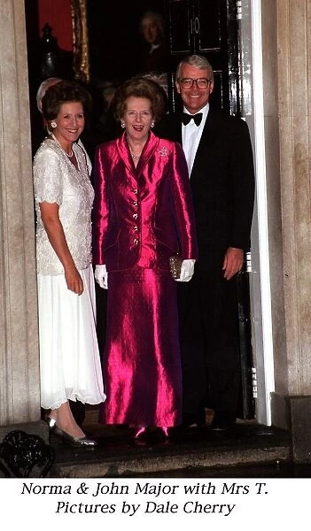 Margaret Thatcher wearing a long pink dress stands with Prime Minister John Major