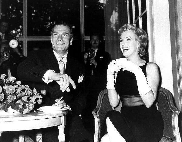 Marilyn Monroe drinking a cup of tea as she sits with Laurence Olivier smoking a