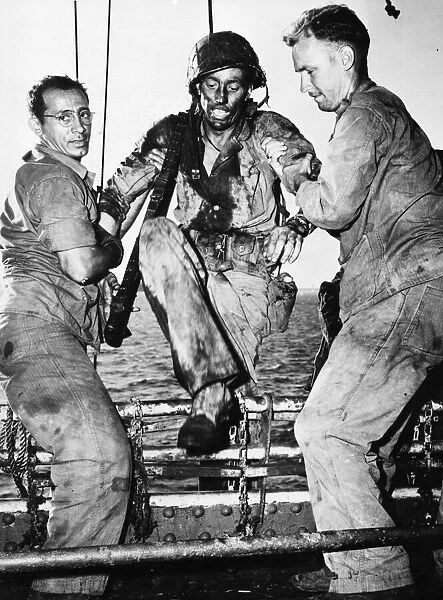 A US marine is assisted onboard a American transport by two Coast Guardsmen after