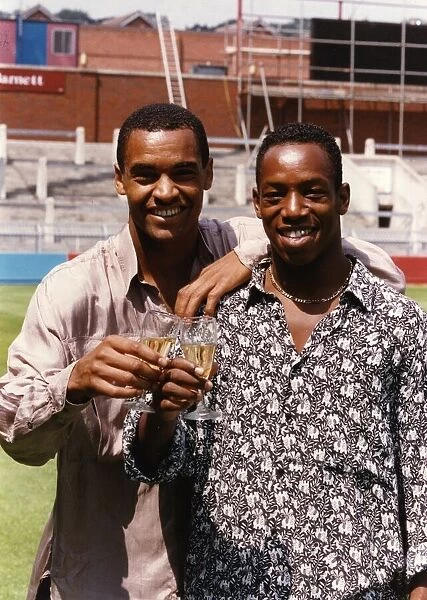 Mark Bright and Ian Wright footballers toast each other with a glass of champagne