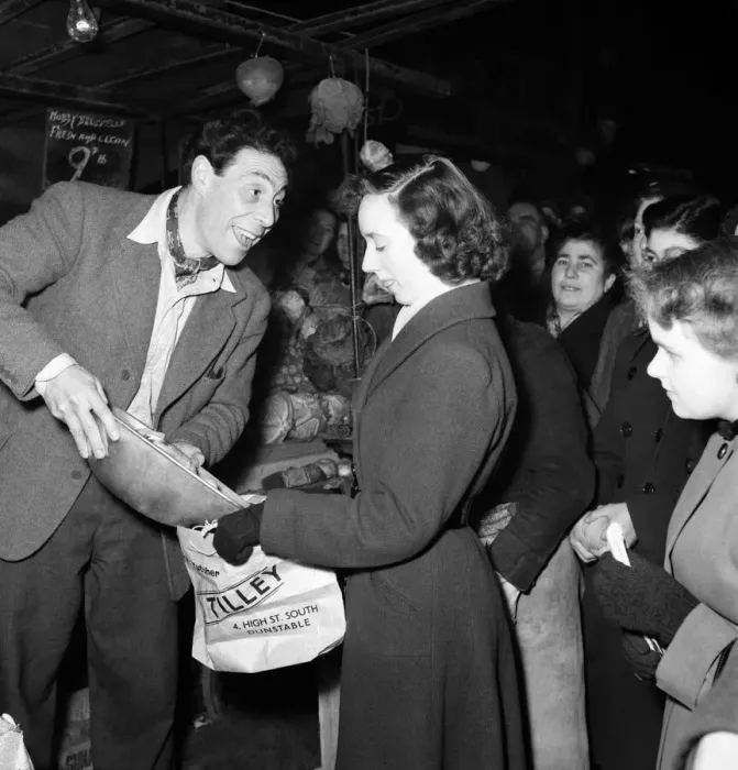 Framed Print : Market trader John Slater sells fruit to a woman on his stall, Chapel Street Market