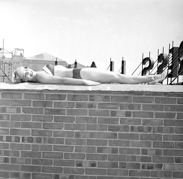 Marlene Lister, July 1955 Young woman sunbathing in bkini on a wall of a roof