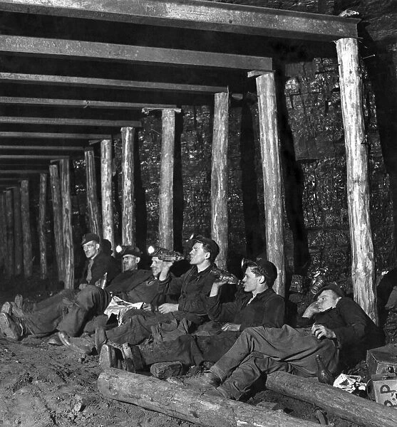 Mechanized coal mining. A group of miners sit down for a rest while working underground