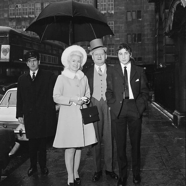 Media Mogul Lew Grade, stands underneath an umbrella with his wife Lady Grade