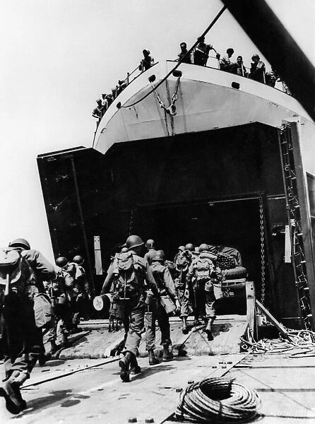 Members of a combat engineer unit march abroad an LST at an English port