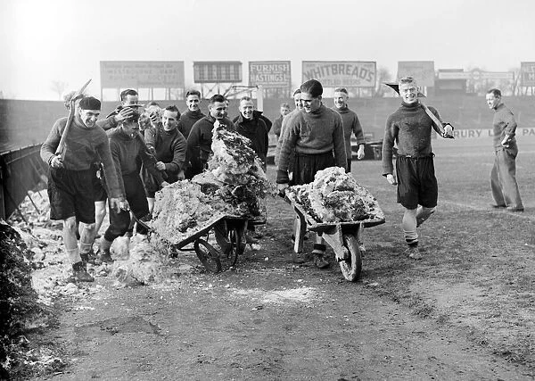 Members of the Fulham football team clearing the snow from their pitch before their FA