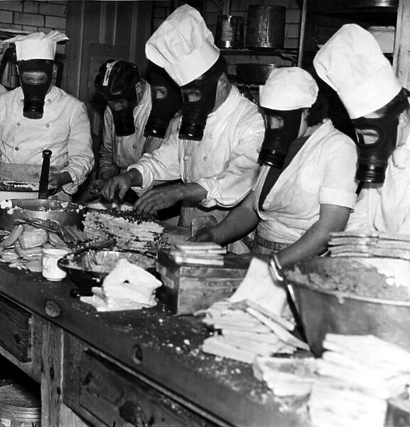 Members of the kitchen staff preparing meals while wearing gas masks during an exercise