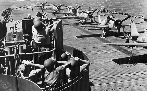 Members of a United States Navy gun crew tt their battle stations scan the sky while