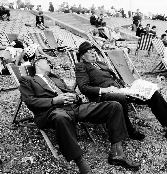 Two men asleep in deckchairs on the beach. August 1964