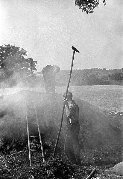 Two men burning peat in a field on a farm in England circa 1938