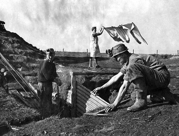 Men working in a coal mine at the bottom of the garden as his wife hangs the washing out