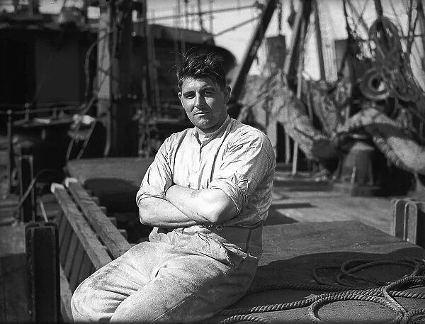A merchant seaman in WW2 sitting on the deck of a ship. Circa 1941