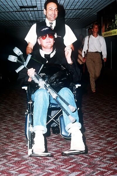 Mike Smith Tv Presenter & DJ being pushed along in wheelchair through the arrivals lounge