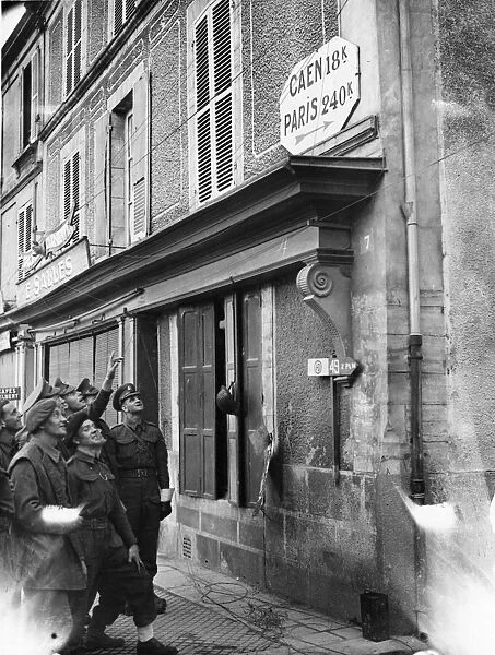 Military police looking at a signpost in the Normandy village of Courseulles which points