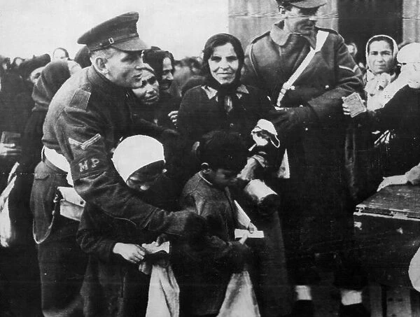 A Military Policeman shepherds children through a crowd to receive rations, Athens