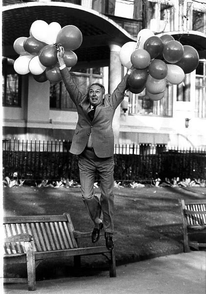 Millionaire airline owner Freddie Laker holding a bunch of balloons after bouncing back