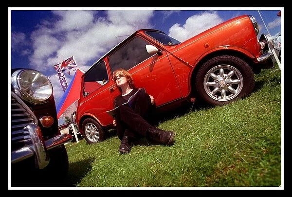 Mini car August 1999 Woman sitting leaning against red Mini in the sun reading brochure