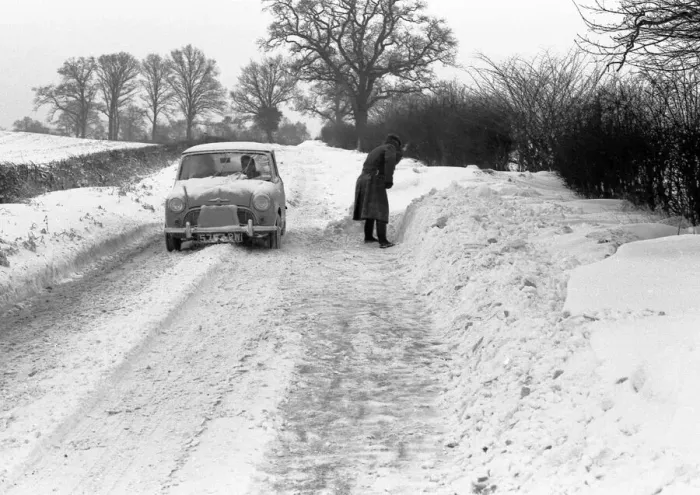 Framed Print : A mini car drives along a snowy lane in the countryside near Coventry whilst a man tries Framed Print : A mini car drives along a snowy lane in the countryside near Coventry whilst a man tries