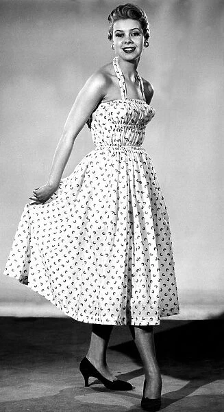 Model from 1950s wearing a dress with a fitted corset style top with a tiny waist