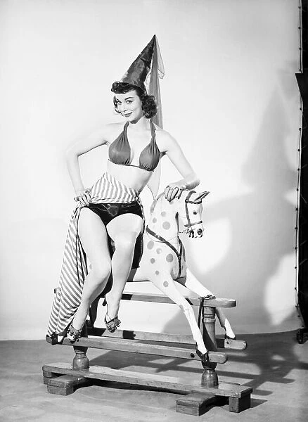 Model dressed as damsel. Riding rocking horse. 1965 E145-001