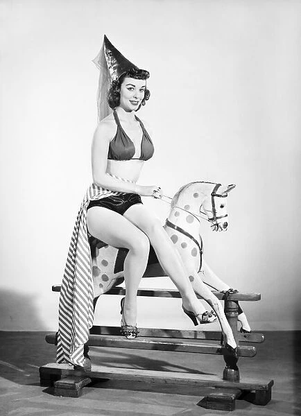 Model dressed as damsel. Riding rocking horse. 1965 E145-004