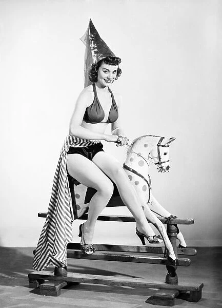 Model dressed as damsel. Riding rocking horse. 1965 E145-006