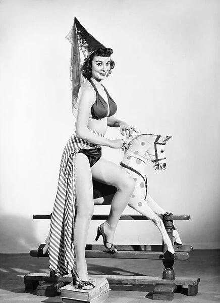Model dressed as damsel. Riding rocking horse. 1965 E145-003
