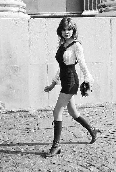 Model and horror film actress Madeline Smith poses wearing hot pants suit with knee high