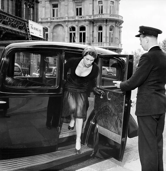 Model Jo Bevan wearing fashions of the day. being helped out from a car by a doorman