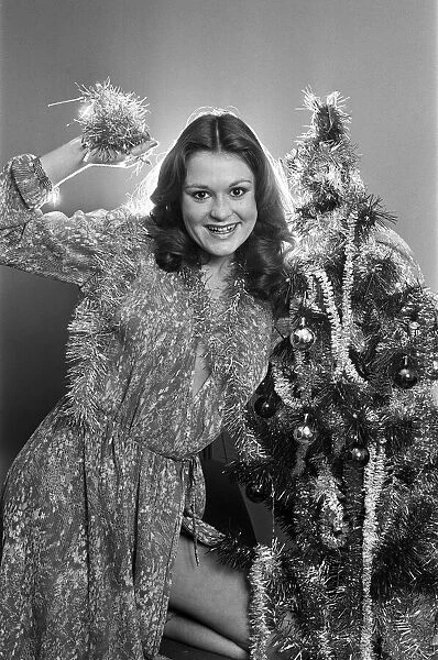 Model Leigh Lesley poses with a Christmas tree. 22nd December 1980