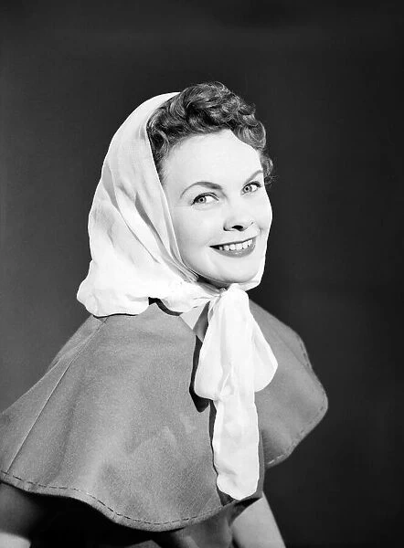 Model Maureen Denham putting on head scarf. July 1956