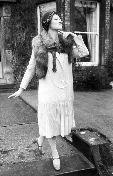 A model posing in an 1920s coat, fox fur and cloche hat