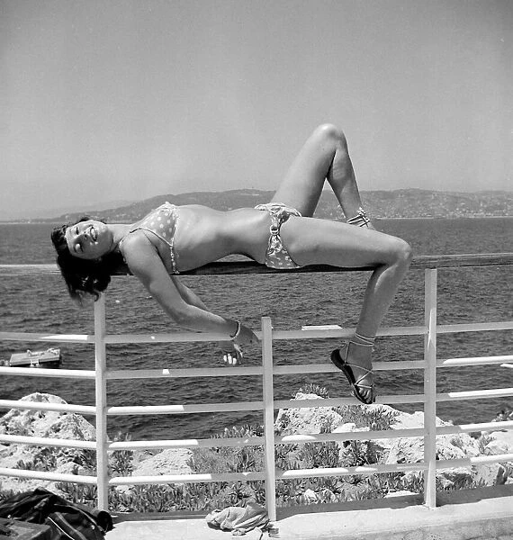 Model posing wearing a bikini lying on railing circa 1949
