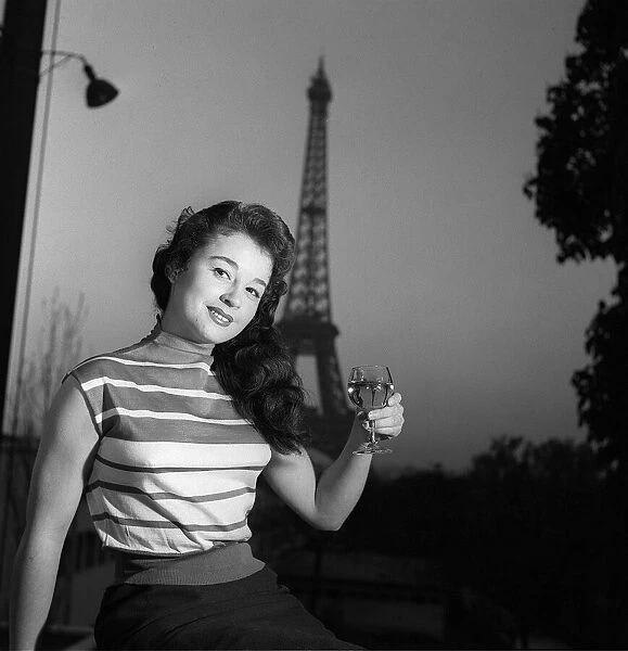 A model raises a glass of wine in front of the Eiffel Tower