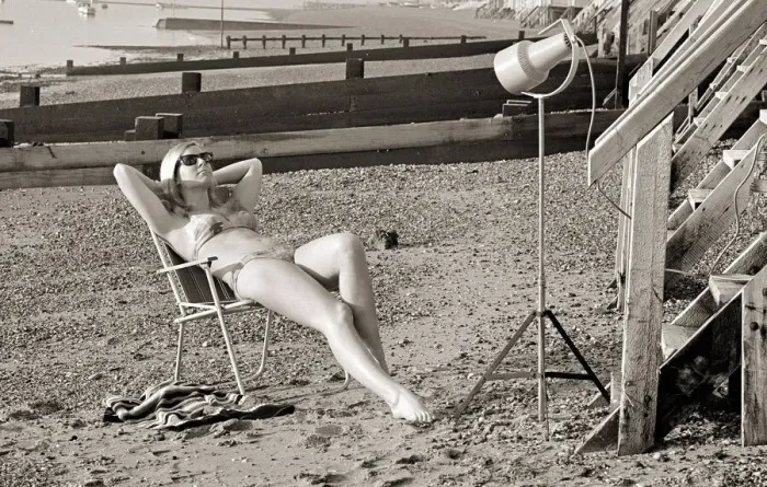 Framed Print : A model sunbathing under a UV lamp on the beach at Cleethorpes November 1967